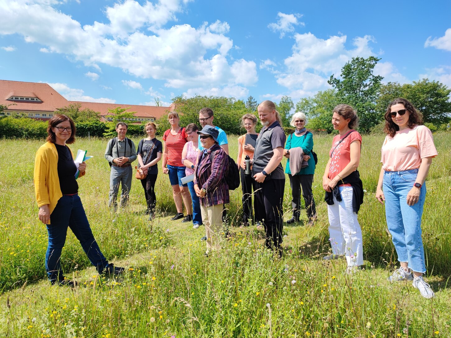 die Seminarleiterin steht mit Seminarteilnehmern auf einer Wiese im LfULG